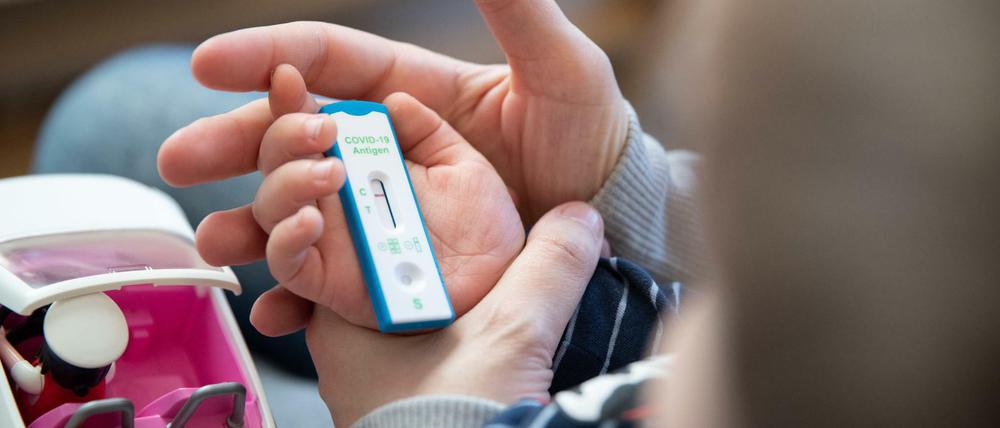 Ein Kita-Kind und seine Mutter warten daheim auf das Ergebnis eines Corona-Selbsttests.