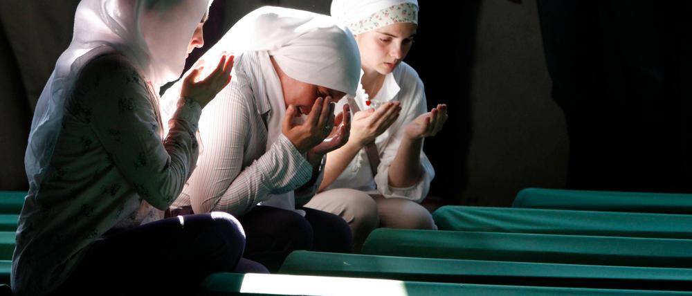 Bosnische Muslimas beten vor Särgen von Opfern des Massakers von Srebrenica, die in einer Gedenkstätte aufgestellt wurden, 2012.