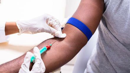 Eine Person nimmt einem Patienten Blut ab.
