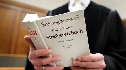 Ein Richter im Gerichtssaal mit Strafgesetzbuch (StGB) in der Hand.