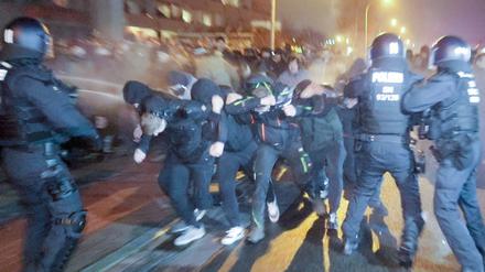 Eine Menschengruppe in Bautzen durchbricht eine Polizeiabsperrung und wird dabei von Einsatzkräften mit Pfefferspray besprüht.