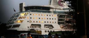 Ein Mann mit Mund-Nasen-Schutz geht an einem Kreuzfahrtschiff vorbei.