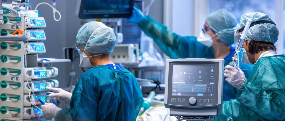 Ärzte und Pflegekräfte betreuen Patienten in einem der Behandlungszimmer auf einer Intensivstation.