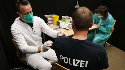 Ein Polizist bekommt eine Impfung.
