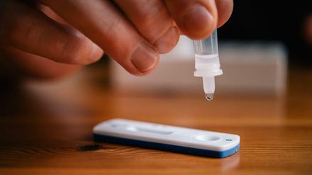 Ein Mann träufelt eine Lösung auf eine Testkassette, die von Covid-19 verursachte Antigene nachweisen kann (Symbolbild).