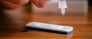 Ein Mann träufelt eine Lösung auf eine Testkassette, die von Covid-19 verursachte Antigene nachweisen kann (Symbolbild).