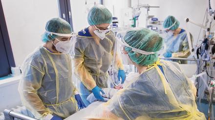 Pfleger und Pflegerinnen tragen Schutzkleidung auf einer Intensivstation für Corona-Patienten. 