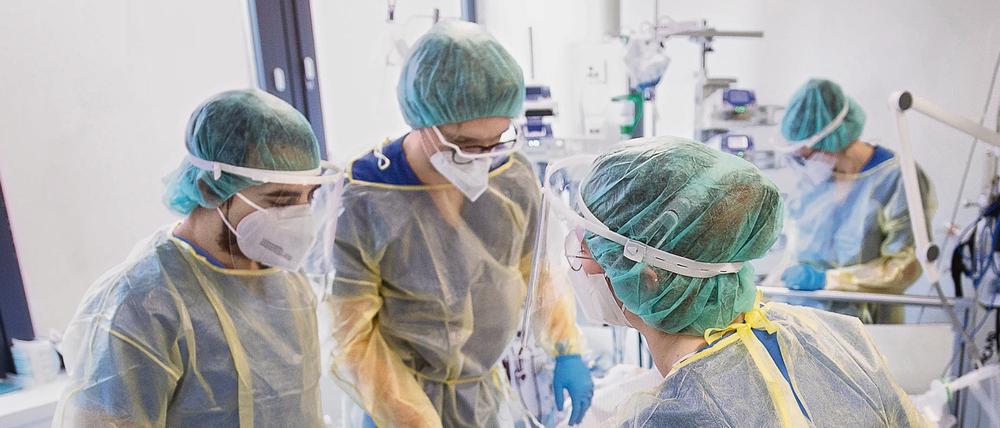 Pfleger und Pflegerinnen tragen Schutzklamotten auf einer Intensivstation für Corona-Patienten. 