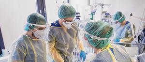 Pfleger und Pflegerinnen tragen Schutzkleidung auf einer Intensivstation für Corona-Patienten.