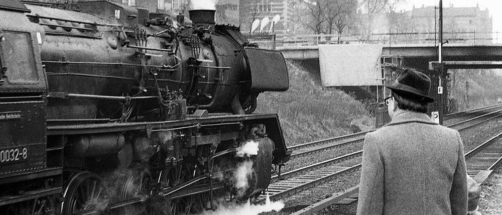 Eine Baureihe 50 fährt 1975 auf dem Ring. Vom S-Bahnsteig Prenzlauer Allee schauen Vater und Kind zu.