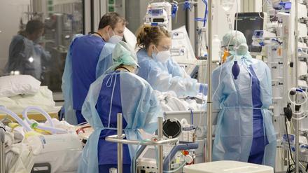 Angestellte auf der Corona-Intensivstation der Charité am Bett einer jungen Patientin.