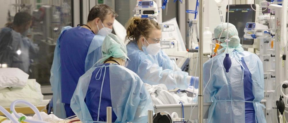 Angestellte auf der Corona-Intensivstation der Charité am Bett einer jungen Patientin.