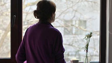 Eine Frau blickt aus dem Fenster – für viele ist das der einzige Blick nach draußen in einer Quarantäne.