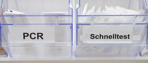 Abstrichstäbchen für PCR-Tests (links) und Corona-Schnelltests liegen in einem Corona-Testcenter in einem Spender.