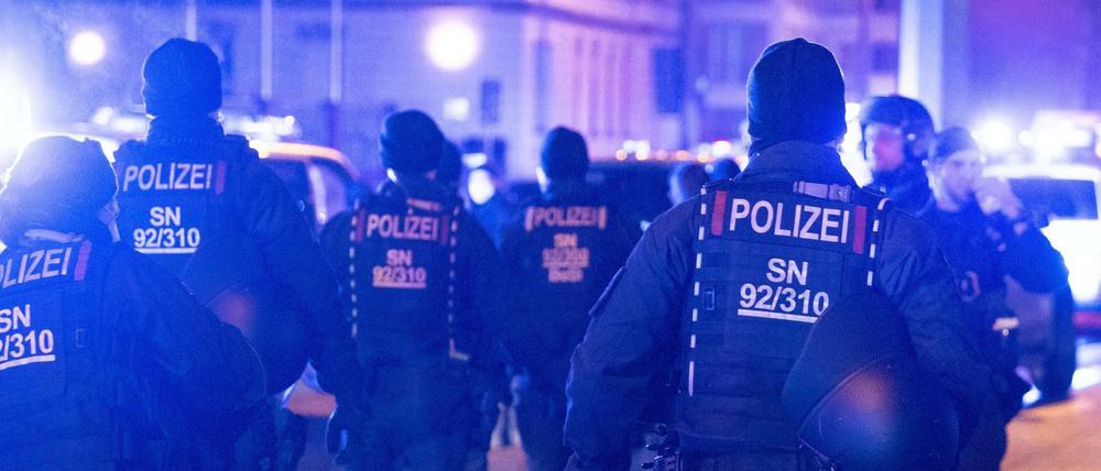 Dresdner Polizisten stehen während eines Protest von Kritikern gegen die Corona-Maßnahmen an einer Straße. 