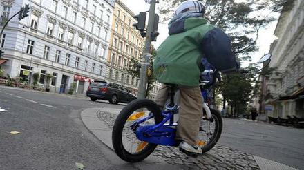 Kind überquert Straße mit dem Rad und fährt auf Gehweg weiter.