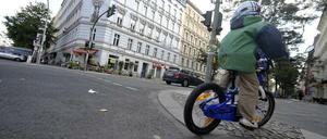 Kind überquert Straße mit dem Rad und fährt auf Gehweg weiter.