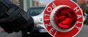 Ein Polizist hält bei einer Sonderkontrolle eine Polizeikelle.