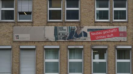 Ein 60er-Jahre Gebäude einer Universitätsklinik, an dem auf Umbaumaßnahmen hingewiesen wird.