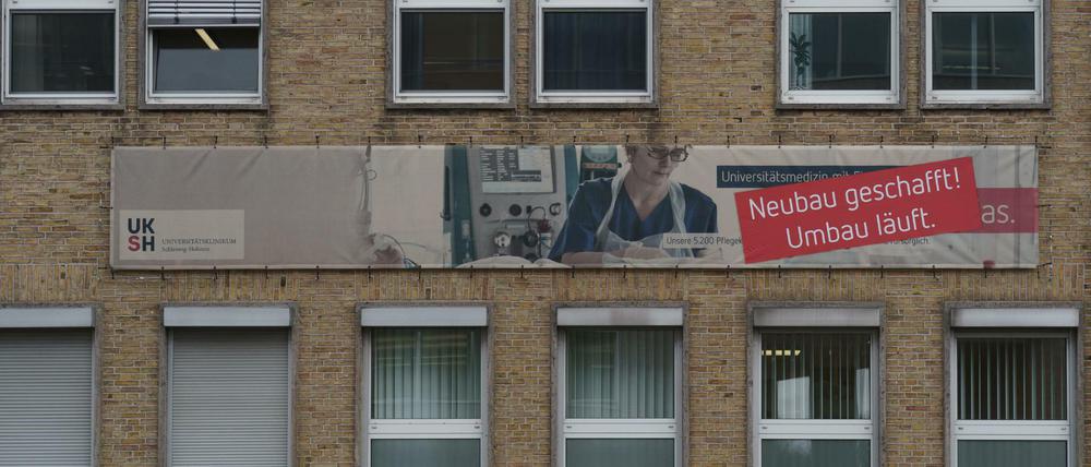 Ein 60er-Jahre Gebäude einer Universitätsklinik, an dem auf Umbaumaßnahmen hingewiesen wird.