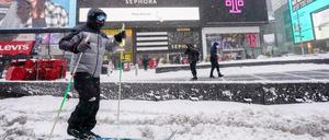 Eine Person fährt während eines Schneesturms auf Langlaufskiern über den Times Square.