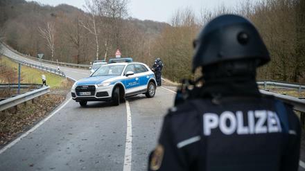 Polizeibeamte stehen an einer Absperrung an der Kreisstraße 22 rund einen Kilometer vom Tatort entfernt.