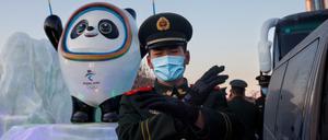 Ein Polizist in Peking vor einem Maskottchen der Olympischen Winterspiele 