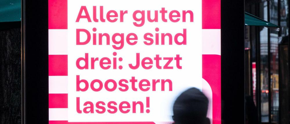 Auf einem Bildschirm wird mit dem Satz «Aller guten Dinge sind drei: Jetzt boostern lassen!» für eine dritte Impfung gegen das Coronavirus geworben.