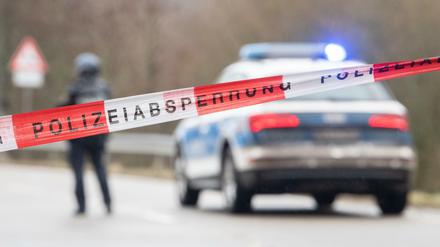 Polizeibeamte stehen an einer Absperrung in der Nähe vom Tatort, an dem zwei Polizeibeamte in Kusel durch Schüsse getötet wurden.