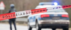 Polizeibeamte stehen an einer Absperrung in der Nähe vom Tatort, an dem zwei Polizeibeamte in Kusel durch Schüsse getötet wurden.
