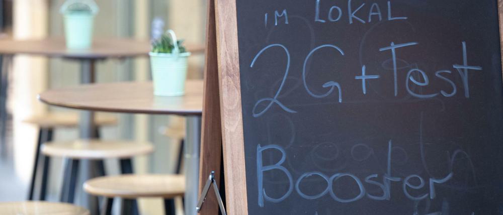 Ein Hinweisschild für die 2G plus Regel steht vor einem Restaurant in der Innenstadt von Stuttgart.