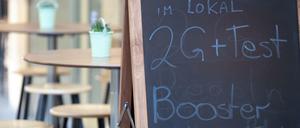Ein Hinweisschild für die 2G plus Regel steht vor einem Restaurant in der Innenstadt von Stuttgart.