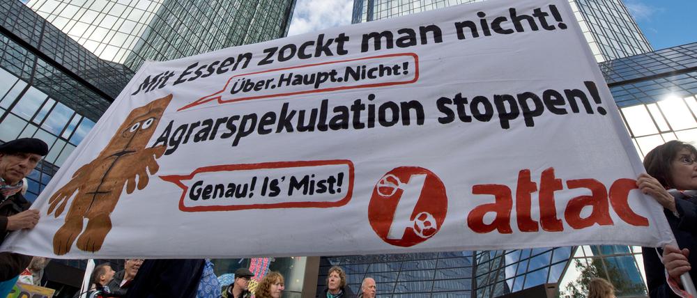 Demonstranten mit einem Attac-Plakat protestieren gegen Lebensmittelspekulation.