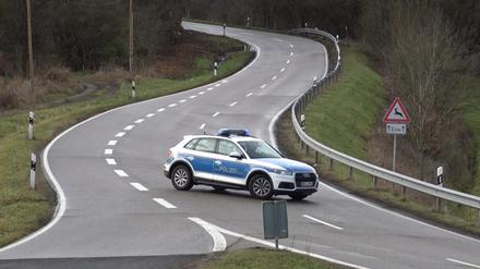 Ein Polizeiauto steht während der Suche nach den Polizistenmördern von Kusel auf einer Straße.