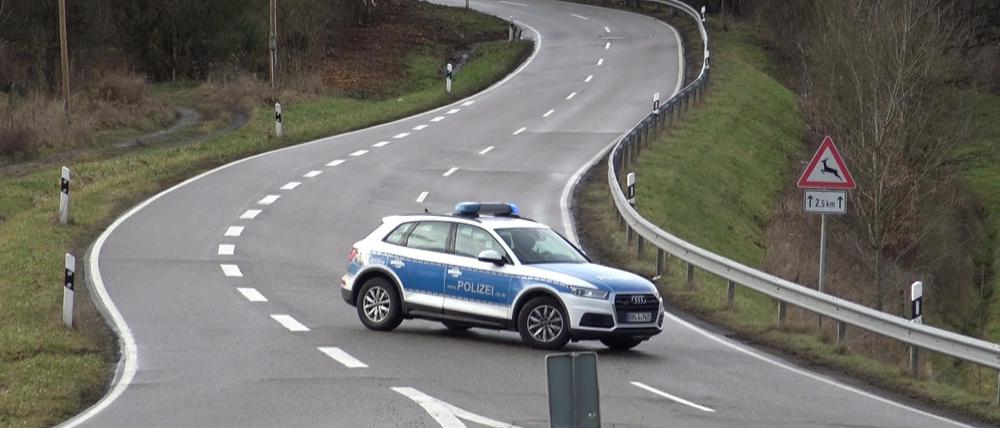 Ein Polizeiauto steht während der Suche nach den Polizistenmördern von Kusel auf einer Straße.