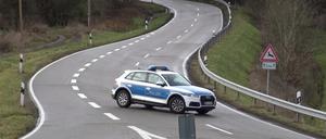 Ein Polizeiauto steht während der Suche nach den Polizistenmördern von Kusel auf einer Straße.