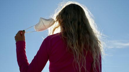 Eine Frau, von hinten fotografiert, nimmt in Madrid ihre Maske ab.