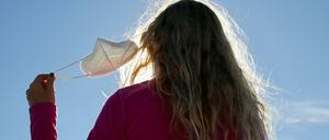 Eine Frau, von hinten fotografiert, nimmt in Madrid ihre Maske ab.