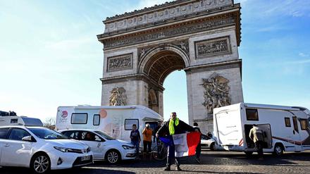 Ein Demonstrant hält am 12. Februar 2022 die französische Flagge vor dem Arc de Triomphe in die Höhe.