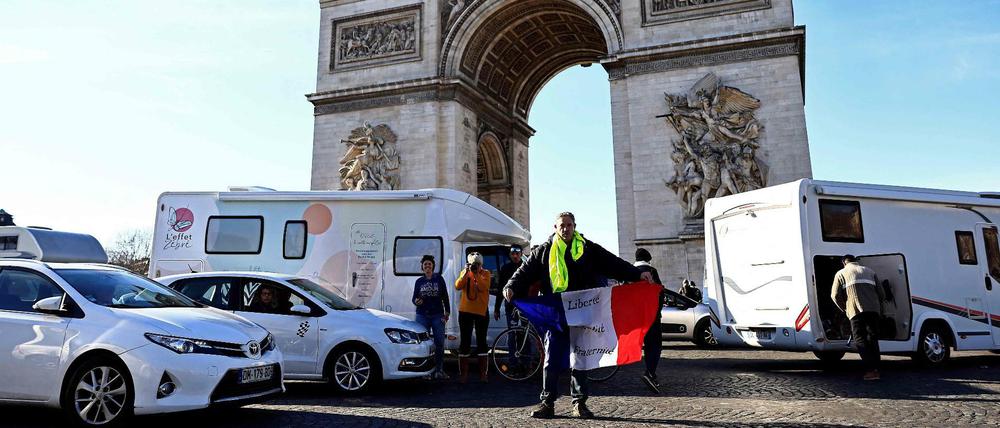 Ein Demonstrant hält am 12. Februar 2022 die französische Flagge vor dem Arc de Triomphe in die Höhe.