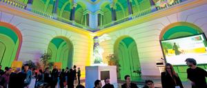 Farbig illuminierter historischer Lichthof einer Universität, in dem sich Menschen zum Austausch treffen.