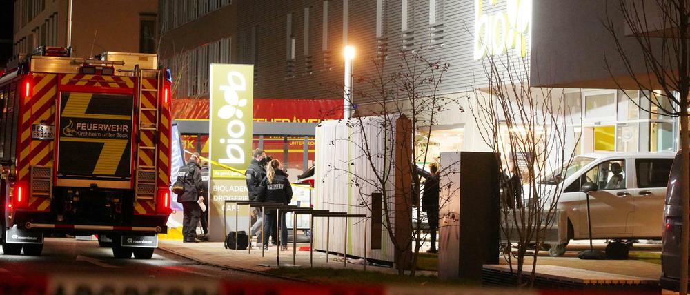 Polizisten und Feuerwehrleute stehen an einem Supermarkt. Dort sind zwei Menschen durch Schüsse ums Leben gekommen.