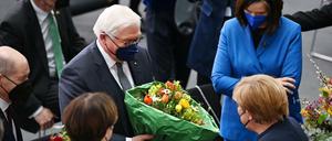 Frank-Walter Steinmeier wird von Angela Merkel beglückwünscht, links ihr Nachfolger als Kanzler Olaf Scholz. 