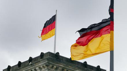 Nicht mehr ganz vollständig: Zerrissene bundesdeutsche Fahnen wehen im Sturm auf und vor dem Reichstagsgebäude.