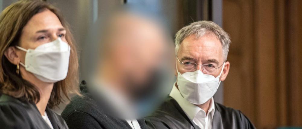 Der Angeklagte steht im Gerichtssaal zwischen seinen Anwälten.