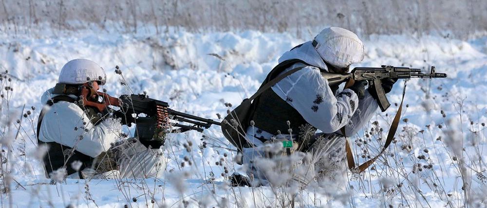 Zwei russische Soldaten, die ihre Schusswaffen während einer Militärübung ausrichten.