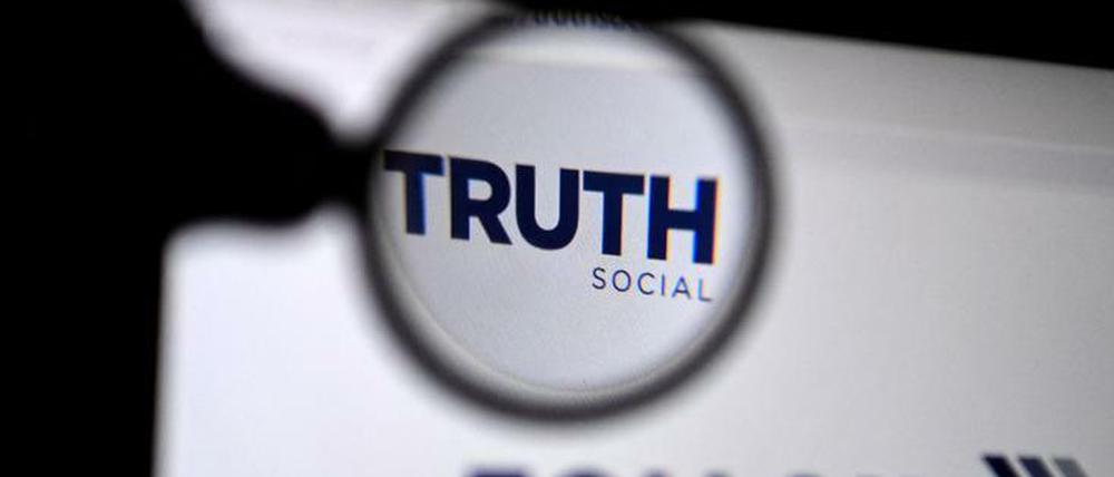 Eine Lupe rahmt den Namen der App Truth Social auf einem Bildschirm ein.