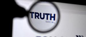 Eine Lupe rahmt den Namen der App Truth Social auf einem Bildschirm ein.