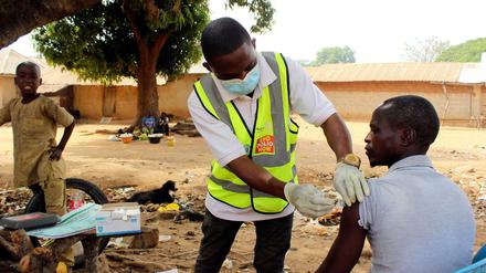 Ein Gesundheitshelfer verabreicht einem Mann den Corona-Impfstoff von AstraZeneca in Sabon Kuje am Rande von Abuja (Nigeria).