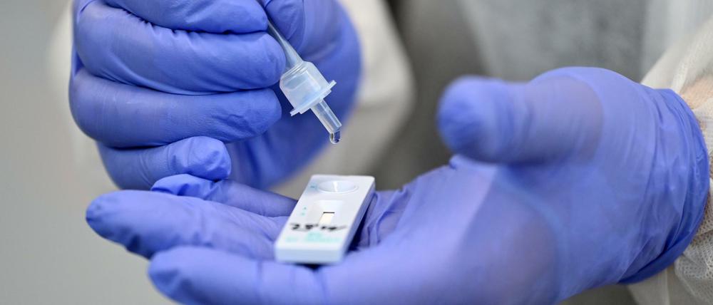 Ein Helfer verarbeitet eine Probe für einen Corona-Schnelltest.